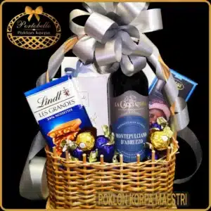 Poklon korpa Maestri sa crvenim vinom Montepulciano i izborom čokolada Lindt, Belgian, Zaini i Ferrero, dekorisana u pletenoj korpi