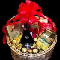 Poklon korpa Chenet Brut sa JP. CHENET penušavim vinom, Jacobs kafom, Lindt Lindor kuglicama i pralinama u pletenoj korpi sa crvenom mašnom